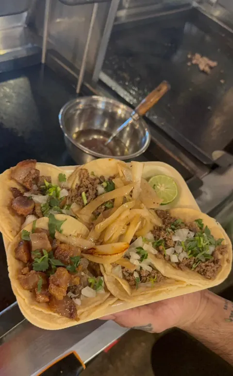 Orden de tacos de chicharrón de cachete y de cecina con cebolla asada, junto a la plancha